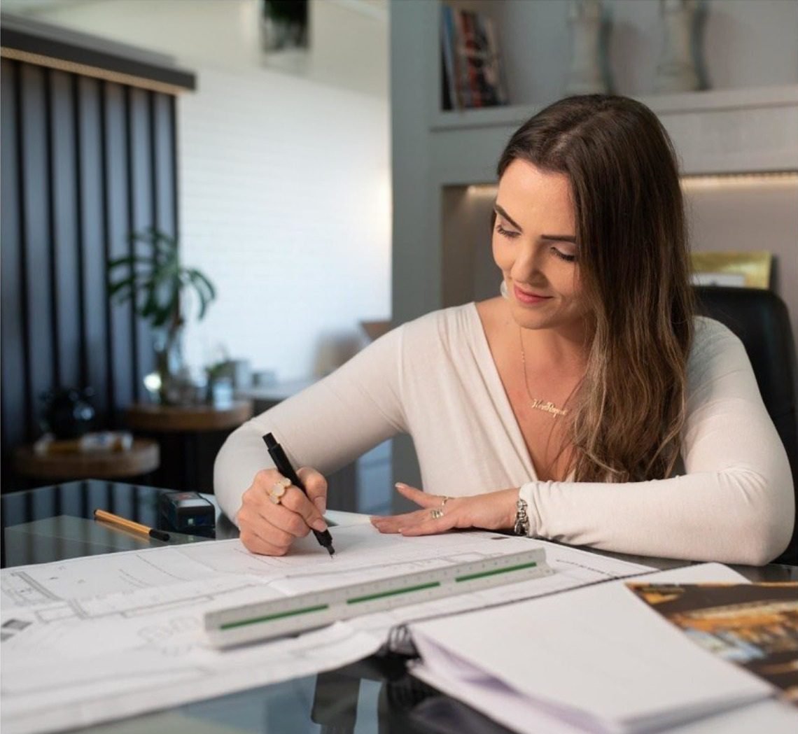 Ana Ferrazzo desenhando sobre a prancheta no escritório